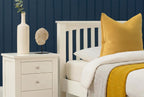 Detailed side view of Boston Soft White Solid Wood 3ft Single Bed Frame with yellow accent pillow and bedside table