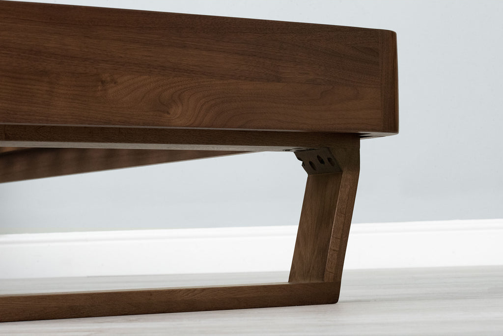 Mayfair solid walnut double bed frame, low-angle close-up of the solid oak sled leg fixed beneath the foot-end rail