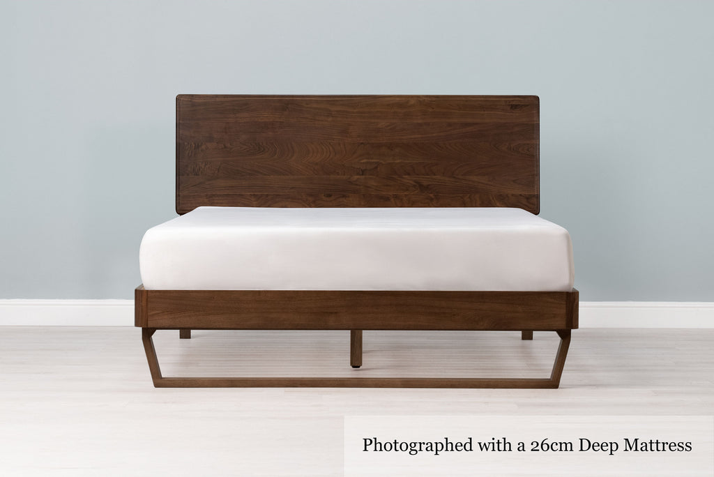 Mayfair solid walnut double bed frame with floating sled leg, a 26cm deep mattress and no bedding, front view