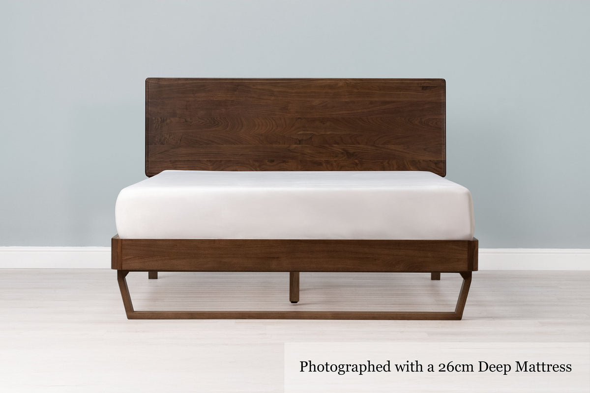 Mayfair solid walnut double bed frame with floating sled leg, a 26cm deep mattress and no bedding, front view