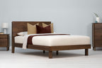 Mayfair solid walnut double bed frame with square legs, angled view with cream bedding, tan and burgundy cushions and matching walnut furniture