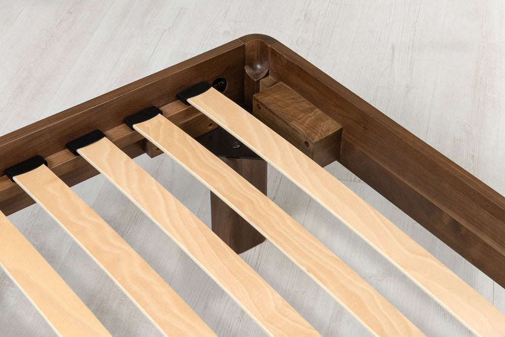 Mayfair solid walnut double bed frame corner close-up, showing the steel corner bracket, corner block and sprung slats