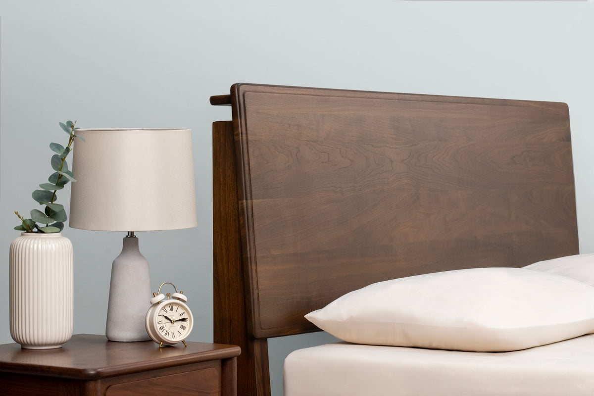 Mayfair solid walnut double bed headboard at its medium height setting, beside a matching walnut bedside table