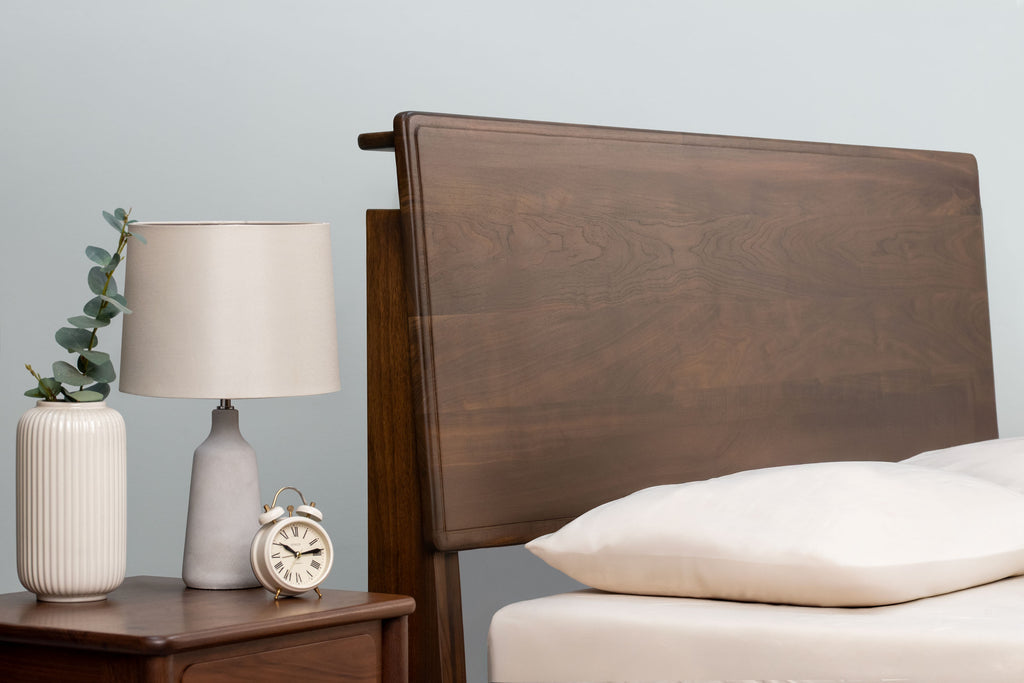 Mayfair solid walnut double bed headboard at its tallest height setting, beside a matching walnut bedside table