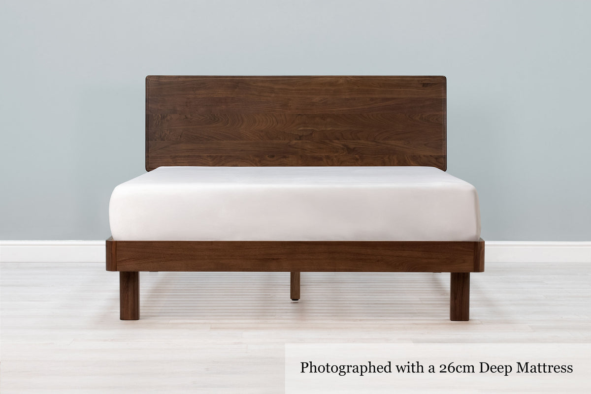Mayfair solid walnut double bed frame with square legs, a 26cm deep mattress and no bedding, front view from the foot of the bed