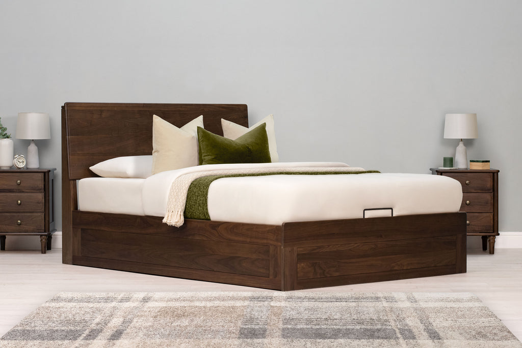 Mayfair solid walnut double ottoman bed frame, angled view with cream and green bedding and matching walnut bedside tables