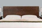 Mayfair solid walnut double ottoman bed headboard, front close-up with two white pillows and a green throw