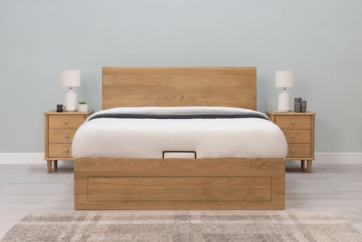 Mayfair Solid Natural Oak Ottoman Storage Bed Frame 4ft6 Double, front view dressed with white bedding and a grey throw