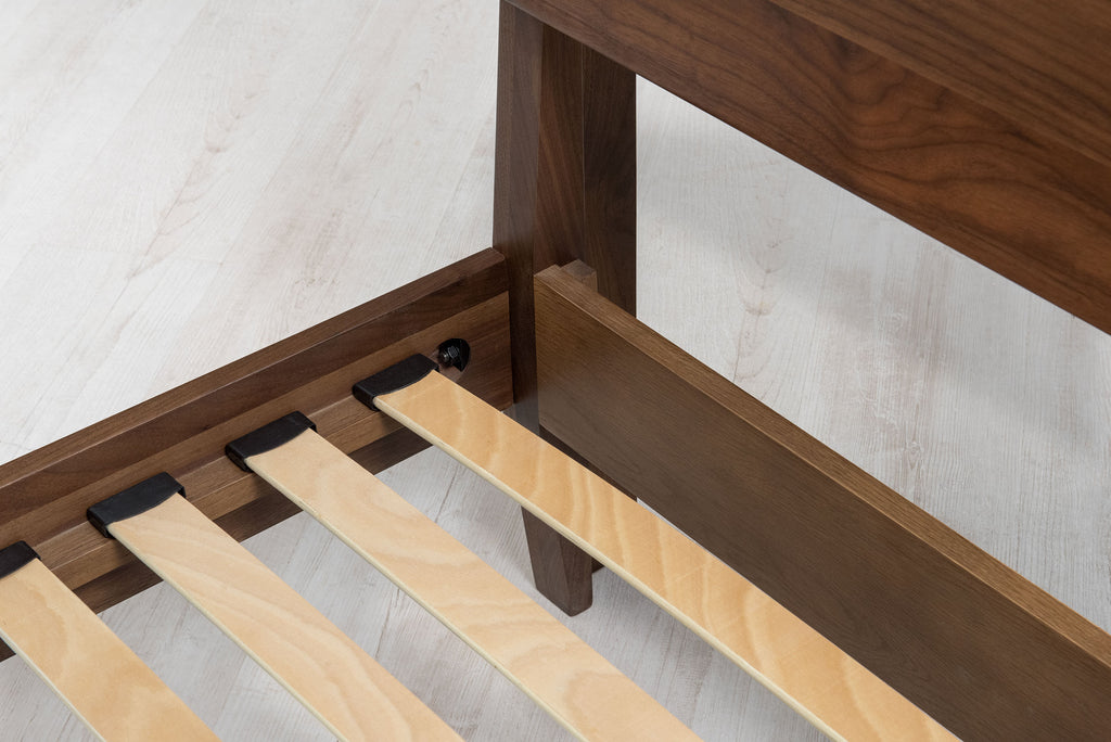 Mayfair solid walnut super king bed frame head-end corner close-up, showing the headboard post, side rail and sprung slats