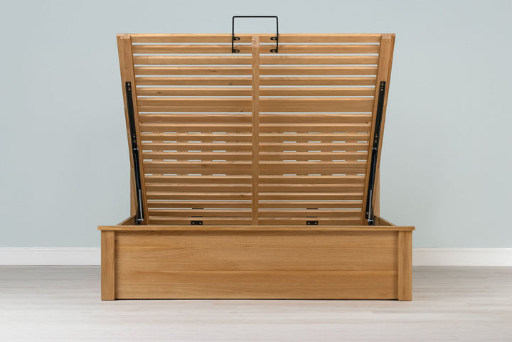 Wilmore solid natural oak double ottoman bed frame without a mattress, front view with the slatted base fully raised