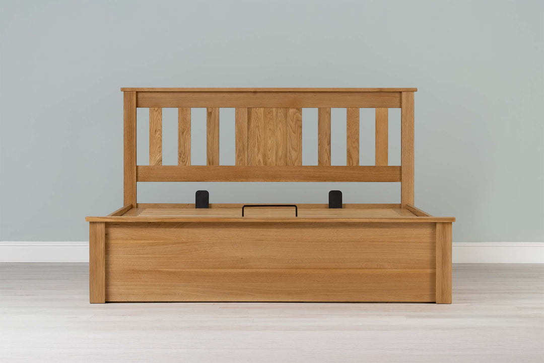 Wilmore solid natural oak king size ottoman bed frame without a mattress, front view from the foot of the bed