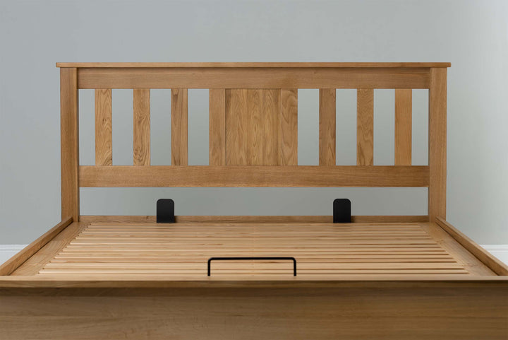 Wilmore solid natural oak king size ottoman bed headboard and slatted base without a mattress, showing the mattress retainer bars