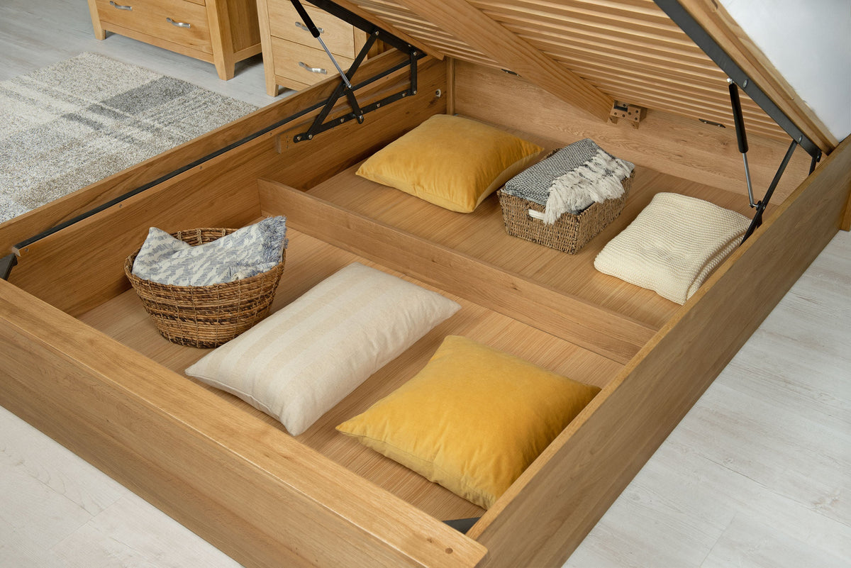 Wilmore solid natural oak king size ottoman bed storage area holding cushions, pillows and baskets on the removable base panels