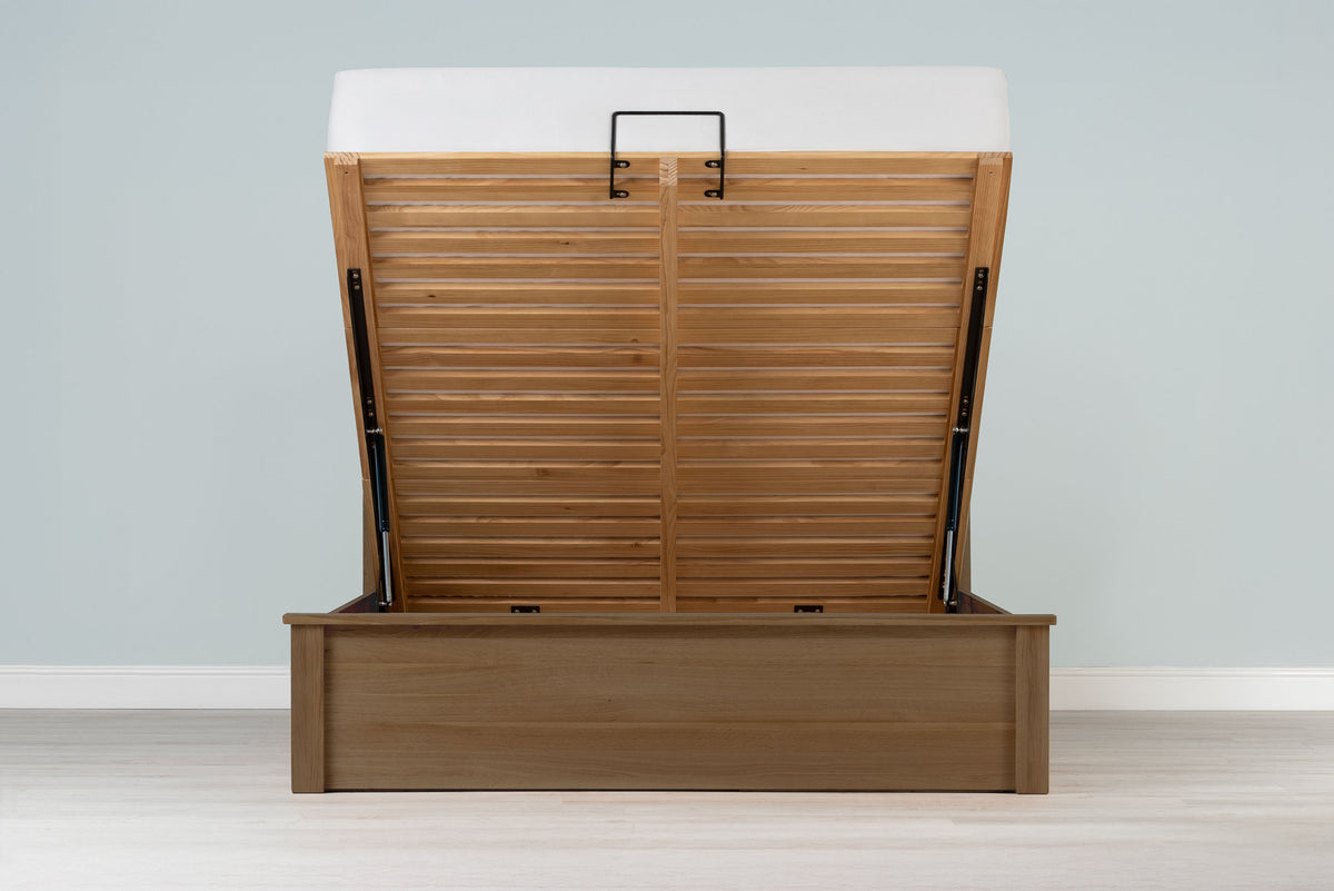 Wilmore solid rustic oak super king ottoman bed frame with a bare mattress and the base raised, front view from the foot of the bed